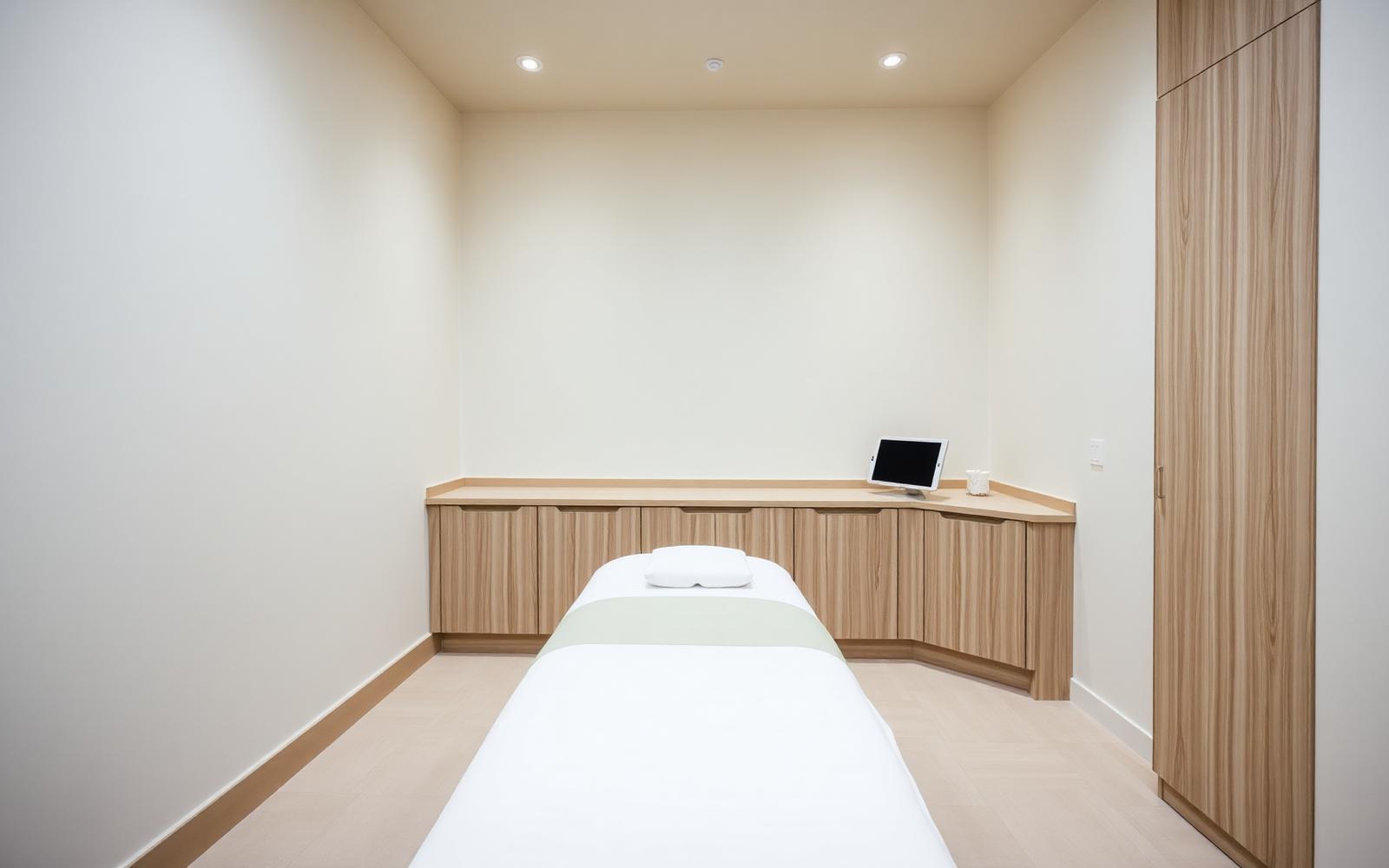 A calm, minimal professional wellness studio treatment room in warm neutral tones